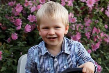 Small boy in front of some flowers