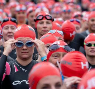 people standing getting ready to swim in the serpentine with red caps