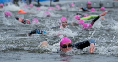 people swimming in the serpentine with pink caps