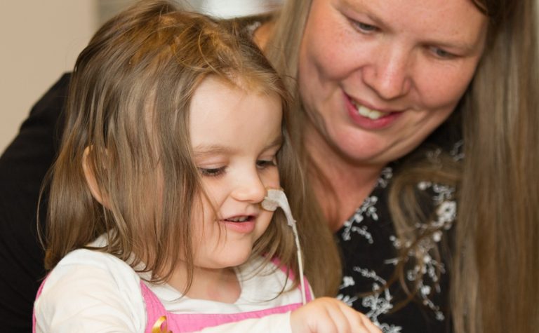 Lucy who was diagnosed with a brain tumour sitting on her mother's lap