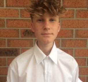 Young man standing in front of a brick wall