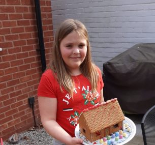 Girl holding gingerbread house