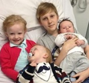 Jarvis sits in hospital bed surrounded by his younger siblings.