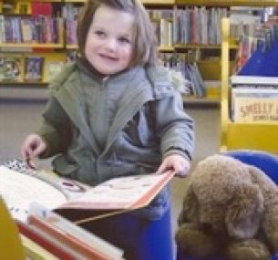 Louisa opens a book in a library.