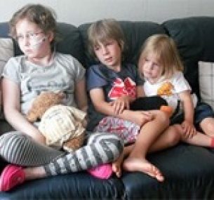 Olivia sits on sofa accompanied by her siblings.