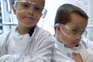 Two boys wearing white lab coats and glasses