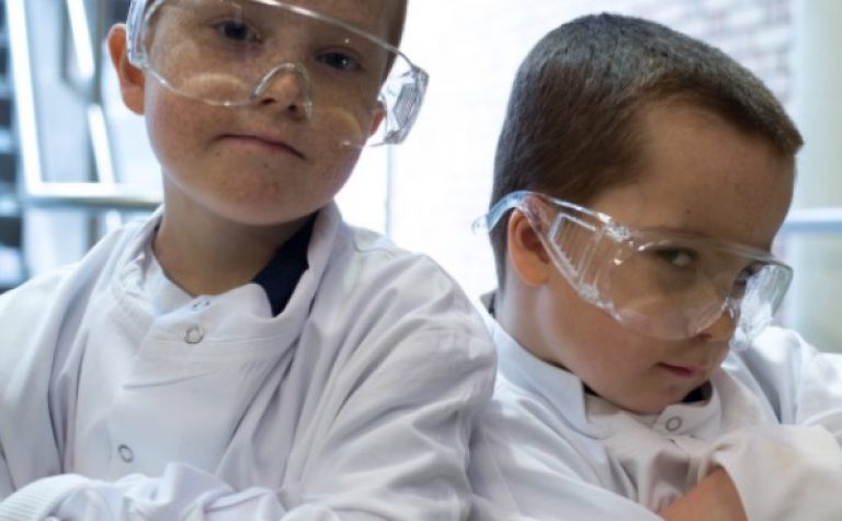 Two boys wearing white lab coats and glasses