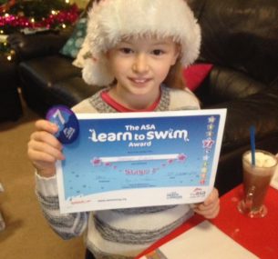 Bethan in santa hat holding swimming certificate