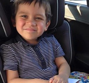 Benji smiling in car after treatment for leg leukaemia