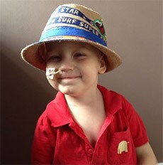 Dylan smiling with a hat on and a tube up his nose