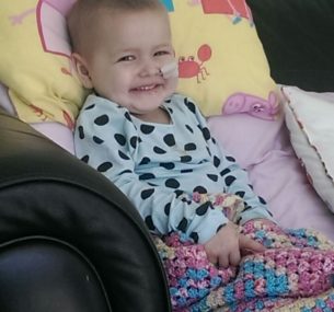 A small child smiling on a sofa