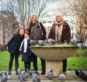 A family stands with a group of pigeons