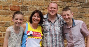 Sam's family poses in front of a brick wall