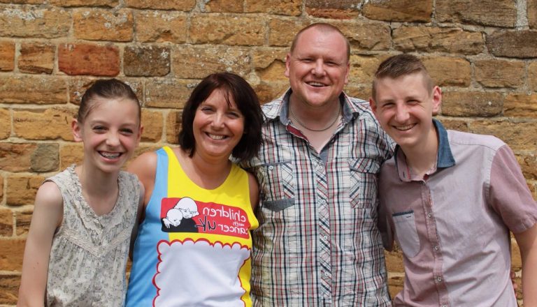 Sam's family poses in front of a brick wall