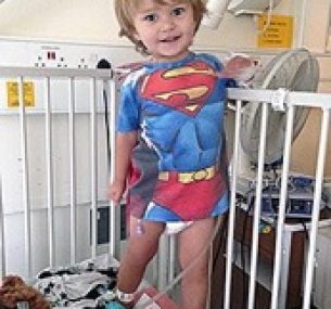 little boy smiling wearing a superman t shirt