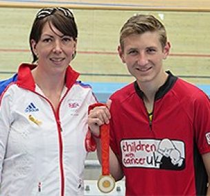 Two people at a velodrome with a medal