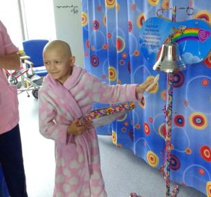 young girl in the hospital ringing the end of treatment bell