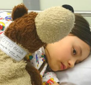 young girl in bed holding a stuffed animal