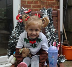 Blonde girl in Christmas jumper sitting on chair