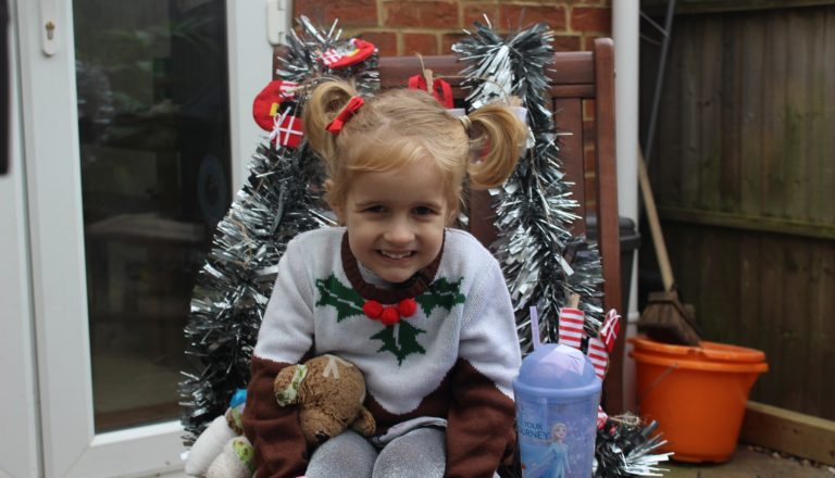 Blonde girl in Christmas jumper sitting on chair