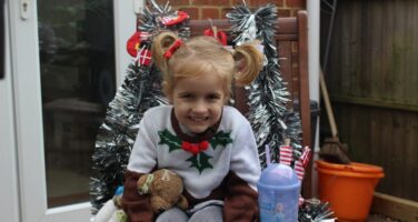 Blonde girl in Christmas jumper sitting on chair