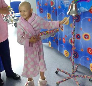A little girl ringing the end of treatment bell