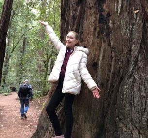 Girl in white jacket in front of tree