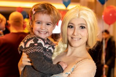 Elsa holding a child at the London Christmas party