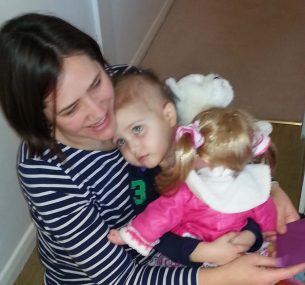 girl cuddling mum with doll