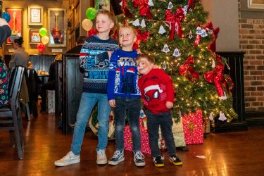 Three children at the Christmas tree at the Manchester Christmas party