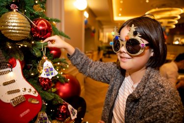 Vega putting a bauble on the tree at the London Christmas party (1)