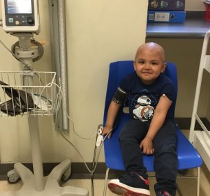 Boy with no hair in hospital chair getting a check-up