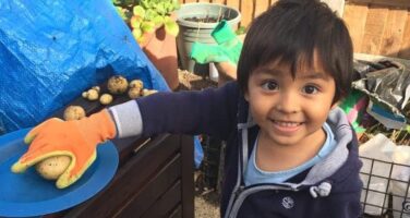 Boy in red wellies holding a potato