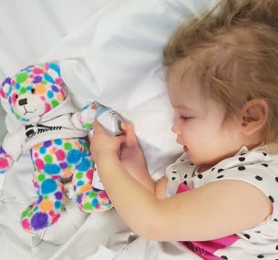 Girl in hospital bed with multi-coloured spotted toy