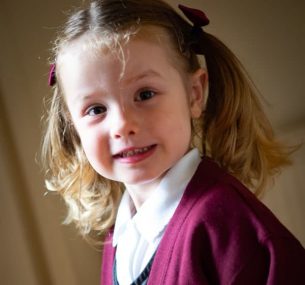 Girl with hair in bows and in maroon school uniform