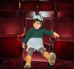 Girl with flower headband sitting on cinema chair