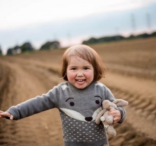 Girl with bunny jumper and toy in field