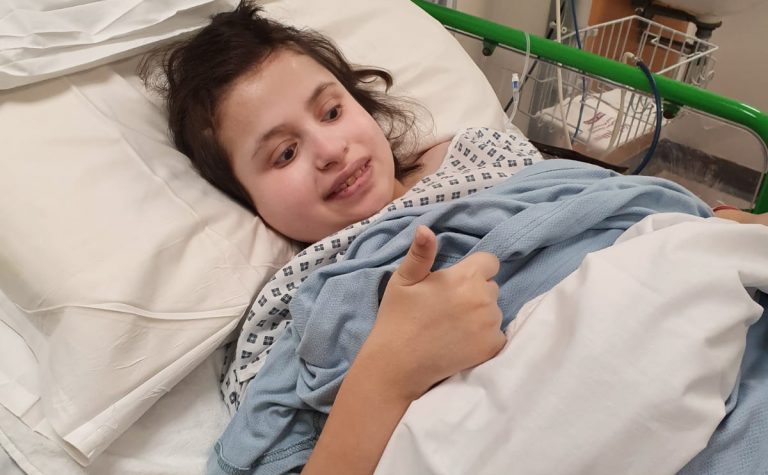 Girl in hospital bed with thumbs up
