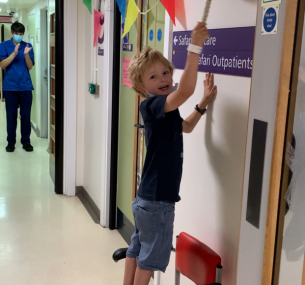 Boy standing on chair ringing the end of treatment bell