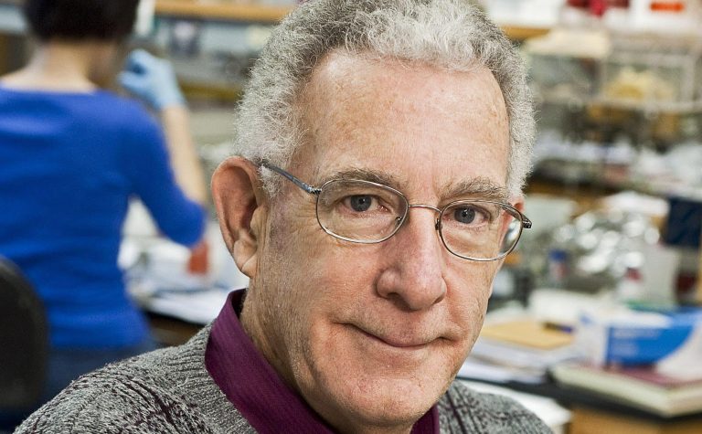 man with grey hair wearing glasses in a lab professot tom seyfried