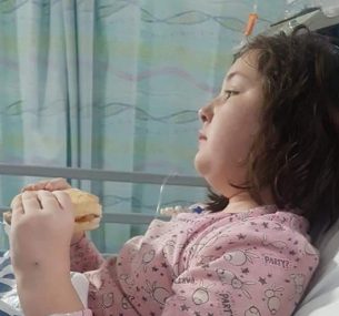 Girl in hospital bed eating sandwich