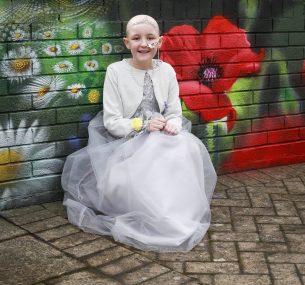 Girl in princess dress in front of flower wall