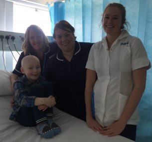 Boy in hospital bed surrounded by nurses