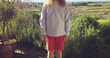 Boy with long hair and pink shorts