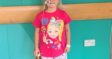 Girl in pin top in hospital with feeding tube
