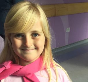 blonde girl with pink jumper wrapped around neck