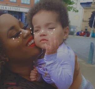 mother holding up young daughter and smiling