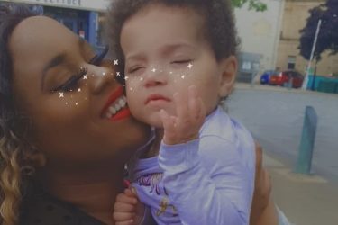 mother holding up young daughter and smiling