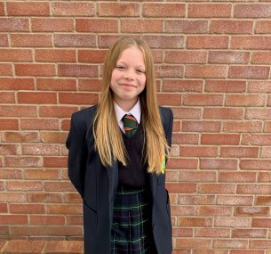 Girl in school uniform standing in front of brick wall