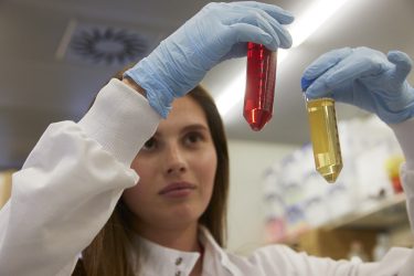 female researcher looking at liquids in tubes